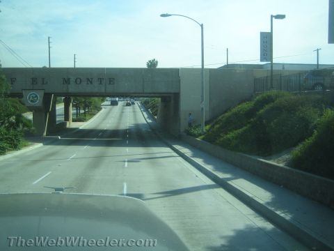 1990 Ford Bronco - Driver's view of a highway passing under a concrete overpass labeled El Monte, with hills and signage alongside.