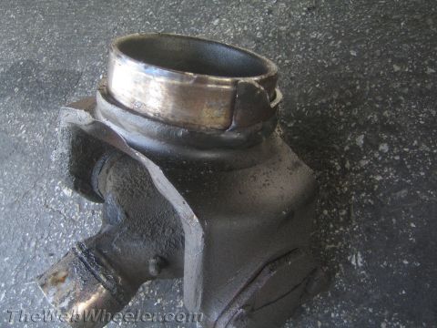 1990 Ford Bronco - cast-metal yoke and bearing component, likely from a driveshaft or differential, sitting on pavement.