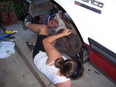 1991 Ford Bronco - Two individuals are seen working on the brake assembly of a 1991 Ford Bronco XLT.