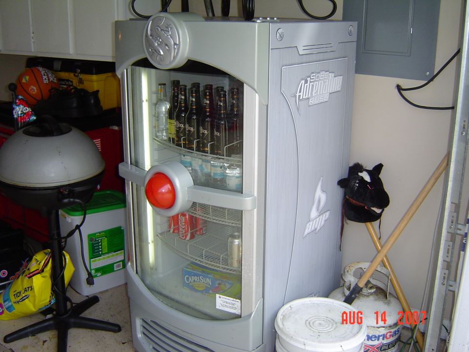Tall silver beverage cooler stocked with bottles in a garage