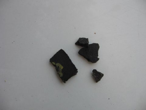 1992 Ford Crown Victoria - Fragments of black material, possibly from a vehicle part, are scattered on a white surface.