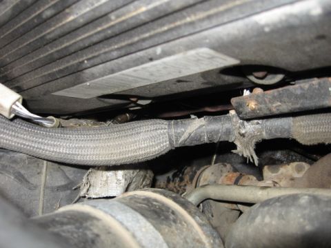 1992 Ford Crown Victoria - Close-up view of a frayed and damaged wiring harness within an engine bay, with visible rust on surrounding components.