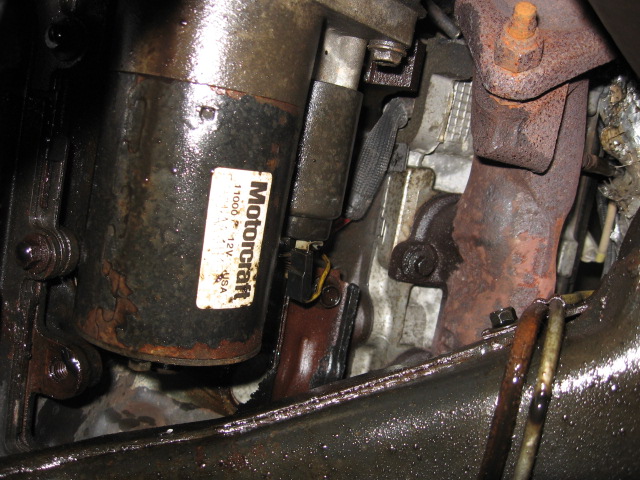 Motorcraft starter motor with 12V USA label, next to rusty exhaust manifold
