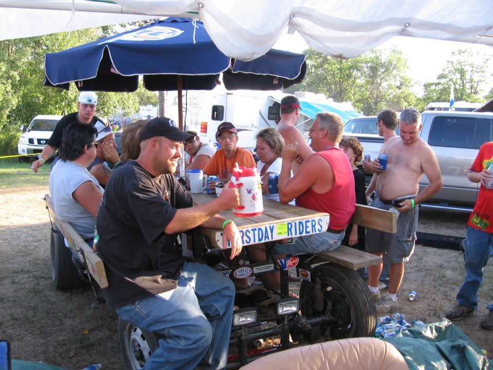 Group of people sitting around a picnic table under a canopy
