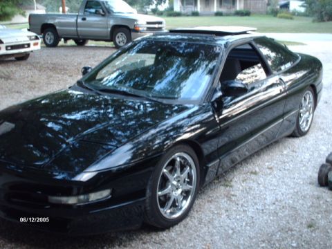 1995 Ford Probe - A black 1995 Ford Probe is parked outside with other vehicles visible in the background.