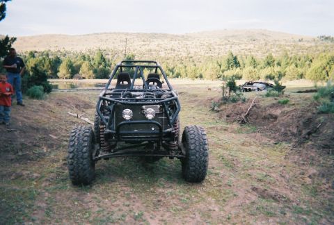 1984 Ford Bronco - A custom-built buggy with a prominent roll cage sits in a rural landscape, with two people standing nearby.