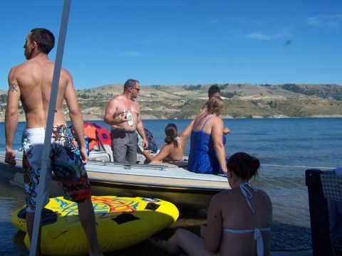 1994 Ford Probe - A group of people relax on a boat near the shore on a sunny day.