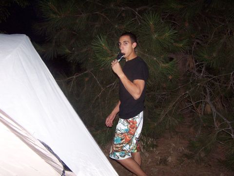 1994 Ford Probe - A young man enjoys a popsicle while standing next to a tent in a wooded area at dusk.
