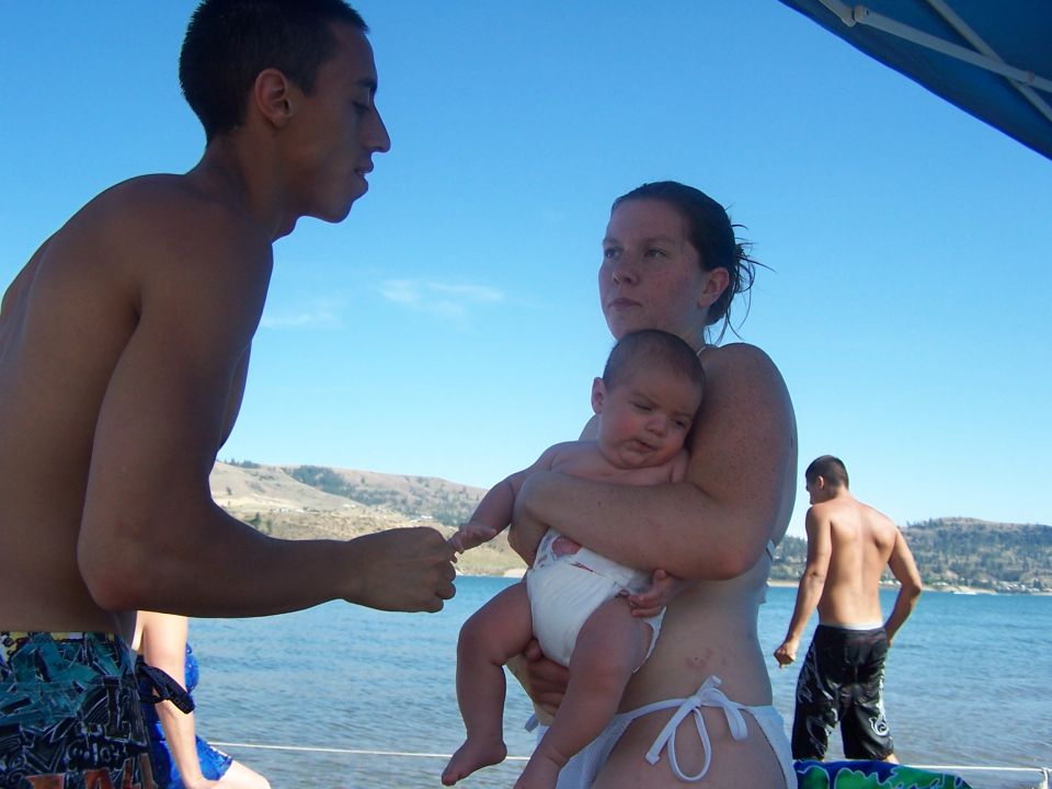 Man and woman holding a baby on a beach with another man in the background