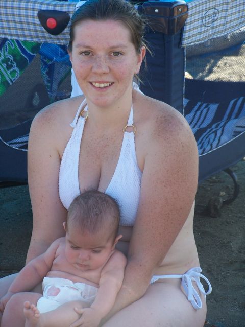 1994 Ford Probe - A woman and a baby sit on the beach with a playpen in the background. The Supermotors logo is visible in the lower right corner.
