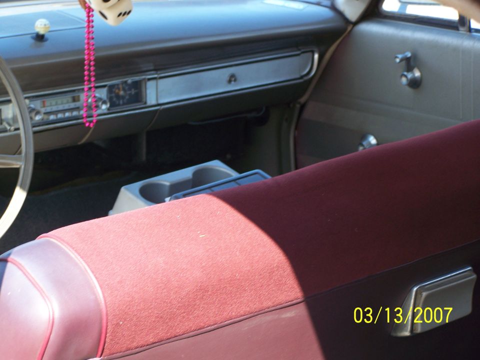 Vintage car interior with red bench seat and dash cupholder