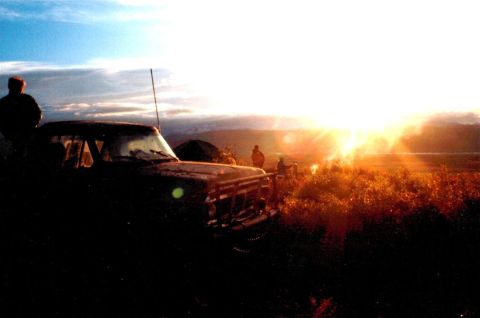 1978 Ford Bronco - A group of people and a vehicle are gathered on a hill as the sun sets.