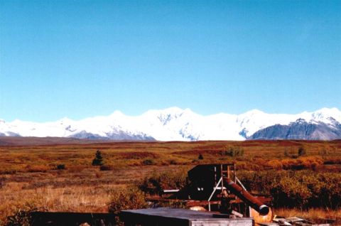 1978 Ford Bronco - A vast landscape under a clear blue sky features snow-covered mountains in the distance and a foreground with autumn foliage and a weathere…