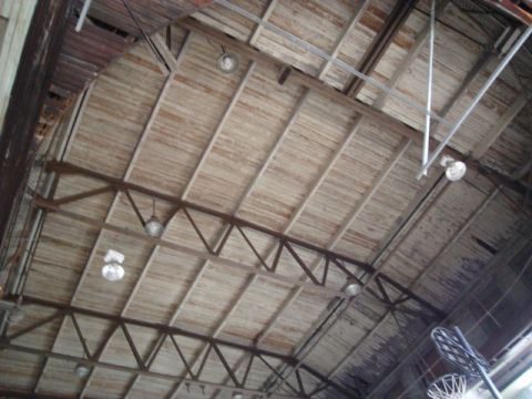 2000 Ford Crown Victoria - The interior of an old building shows a wooden plank ceiling with exposed metal beams and industrial lighting fixtures.