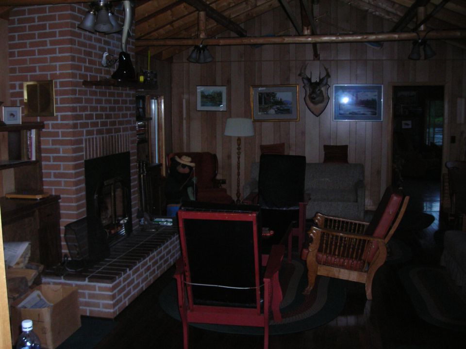 Interior of a rustic room with a brick fireplace, wood paneling, and furniture