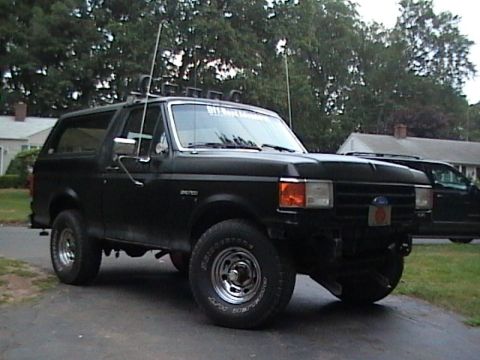 1990 Ford Bronco - This black Ford Bronco is equipped with off-road lights and antennas, suggesting it's ready for adventure.