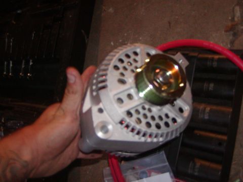 1991 Ford Bronco - A hand holds a vehicle alternator, a crucial component for charging the battery.