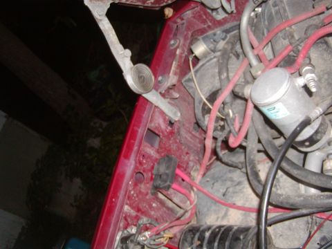 1991 Ford Bronco - Close-up view of engine bay components, including hoses and a silver cylinder, in a red vehicle.