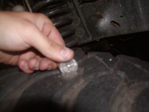 1991 Ford Bronco - A hand is shown holding a coin to the tread of a tire, likely to gauge its depth.
