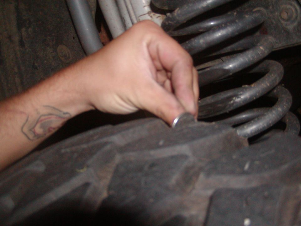 Hand with a coin checking the tread depth on a large off-road tire