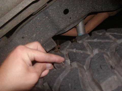 1991 Ford Bronco - A hand points to the tread of a large off-road tire, with the vehicle's frame and suspension visible.