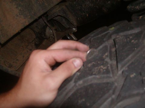 1991 Ford Bronco - A hand holds a coin to the tire tread, likely to show tread depth.