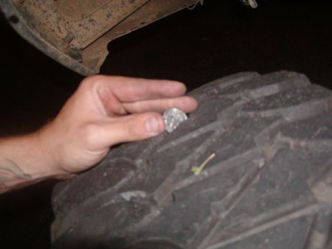 1991 Ford Bronco - A hand is shown holding a coin on the deep tread of a large tire.
