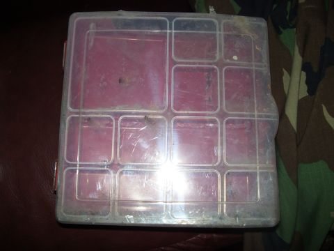 1986 Ford Bronco - A clear plastic organizer box with a red interior sits on a surface, possibly for storing small items.