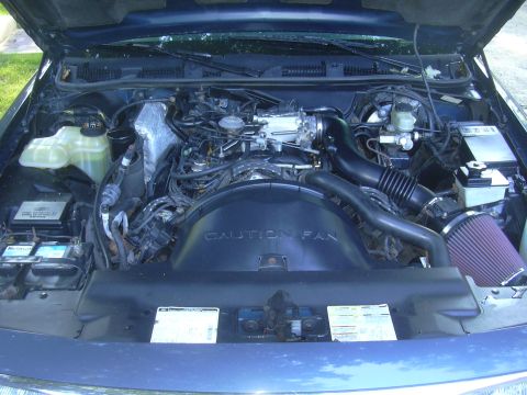 1996 Ford Crown Victoria - The engine bay of a 1996 Ford Crown Victoria is shown, a cone air filter and a prominent fan shroud.