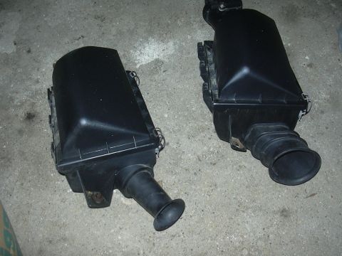 1996 Ford Crown Victoria - Two black plastic air filter housings are shown on a concrete floor.