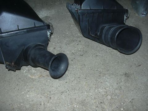1996 Ford Crown Victoria - Two black air intake boxes are shown resting on a concrete surface.