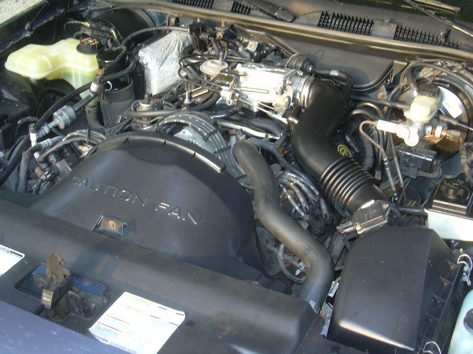 Engine bay with a black fan shroud that says "CAUTION FAN"