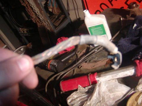 1991 Ford Bronco - A hand holds a worn electrical cable with a ring terminal and a molded connector end, its insulation split and taped in the middle. The bac…