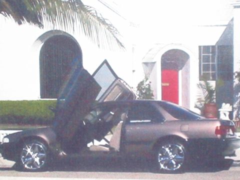 1968 Ford Mustang - This car has custom gullwing doors and aftermarket rims, parked in front of a house.