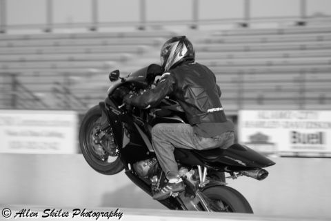2006 Honda CBR-RR - A motorcycle rider performs a wheelie at a drag strip, with blurred bleachers in the background.
