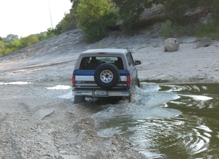 1996 Ford Bronco - Ford Bronco navigates a water crossing on a rocky, off-road trail.