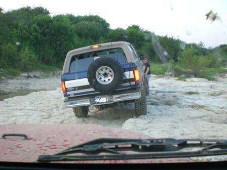 1996 Ford Bronco - A blue and tan 1996 Ford Bronco navigates a rocky, off-road path.