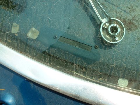 1978 Ford Mustang II - The VIN plate is mounted on the dashboard behind the windshield, obscured by dust and glare.