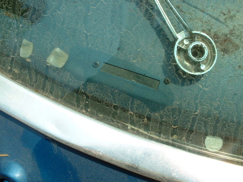 Close-up of a dusty windshield with a VIN plate visible