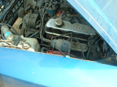 1978 Ford Mustang II - The engine bay of a blue car, a V8 engine and the Supermotors.net watermark.