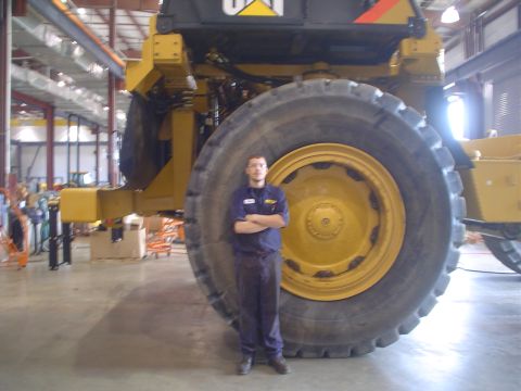 1966 International School Bus - Worker poses next to an enormous tire on a Caterpillar mining truck.