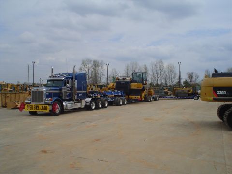 1966 International School Bus - Semi-truck transports large yellow construction equipment on a flatbed trailer.