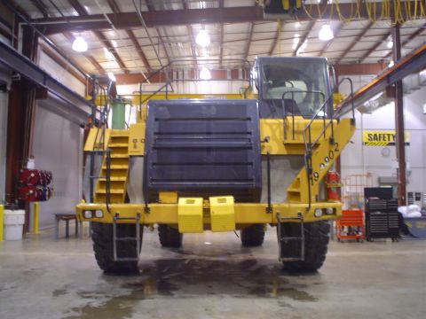 1966 International School Bus - Yellow heavy equipment vehicle with large black grille and wide tires seen from the rear.
