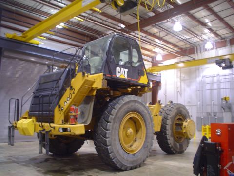 1966 International School Bus - A Caterpillar wheel loader is parked inside a building with industrial lighting and equipment.