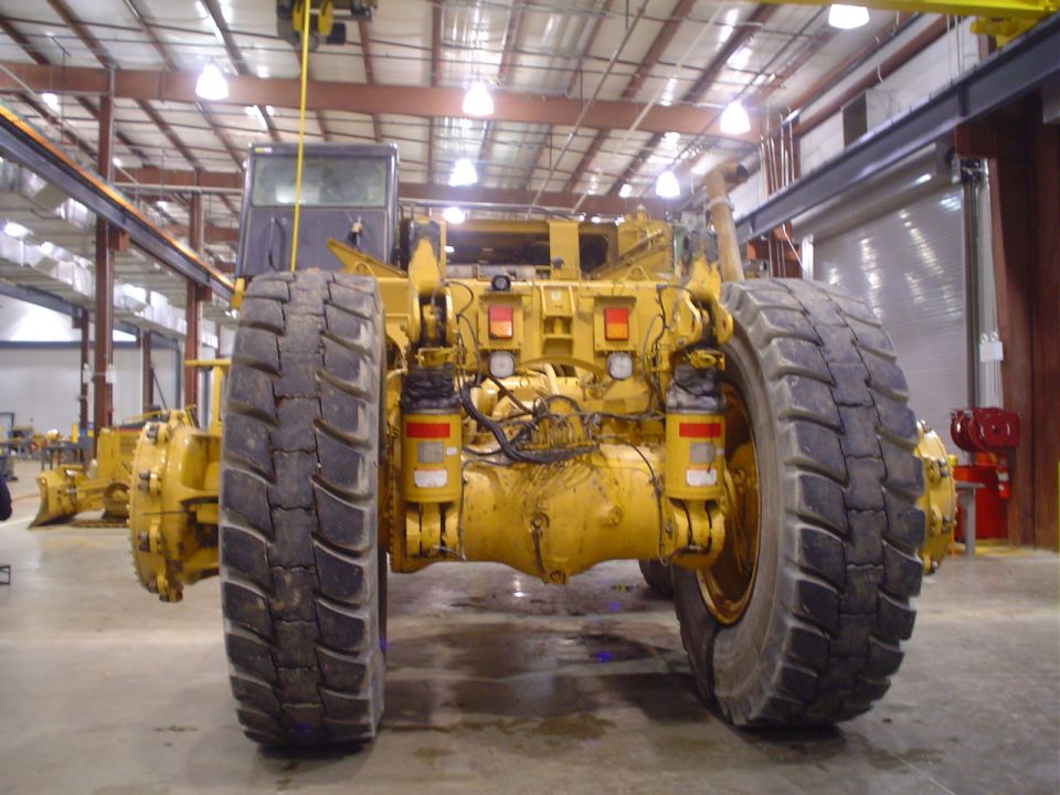 Yellow heavy machinery rear view with large tires and hydraulic components