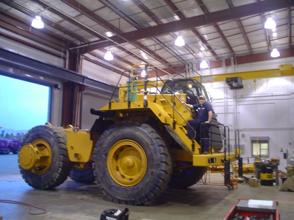 Large yellow articulated wheel loader inside a maintenance shop