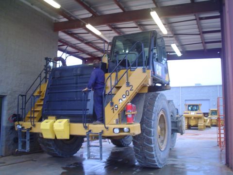1966 International School Bus - Articulated dump truck parked inside a garage with other construction equipment nearby.