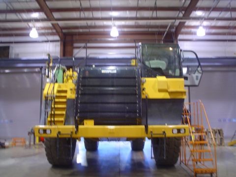 1966 International School Bus - Front view of a yellow Caterpillar mining truck with a large black grille and an orange access ladder.