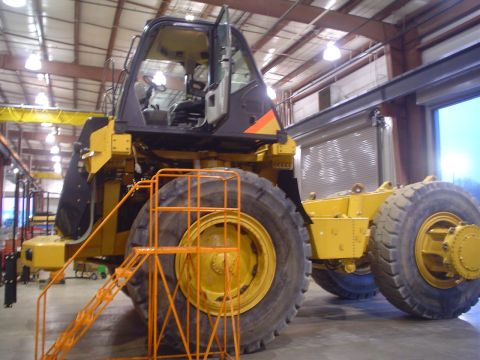 1966 International School Bus - An articulated dump truck, likely a construction vehicle, is shown in a workshop setting with its cab door open.