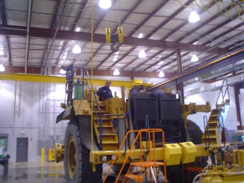 1966 International School Bus - Large yellow mining truck with a worker in the cab, parked inside a large industrial building.